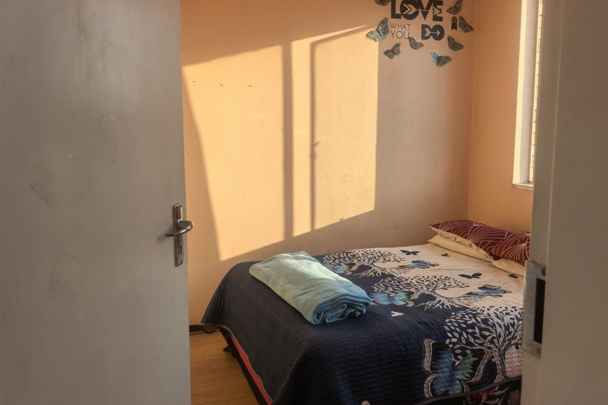 A compact bedroom featuring laminate flooring and natural light, providing a functional space for rest.