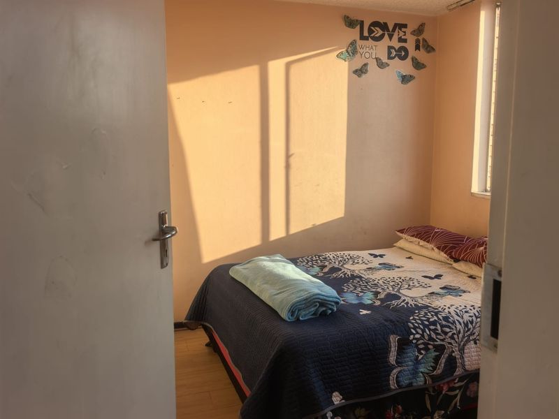 A compact bedroom featuring laminate flooring and natural light, providing a functional space for rest.