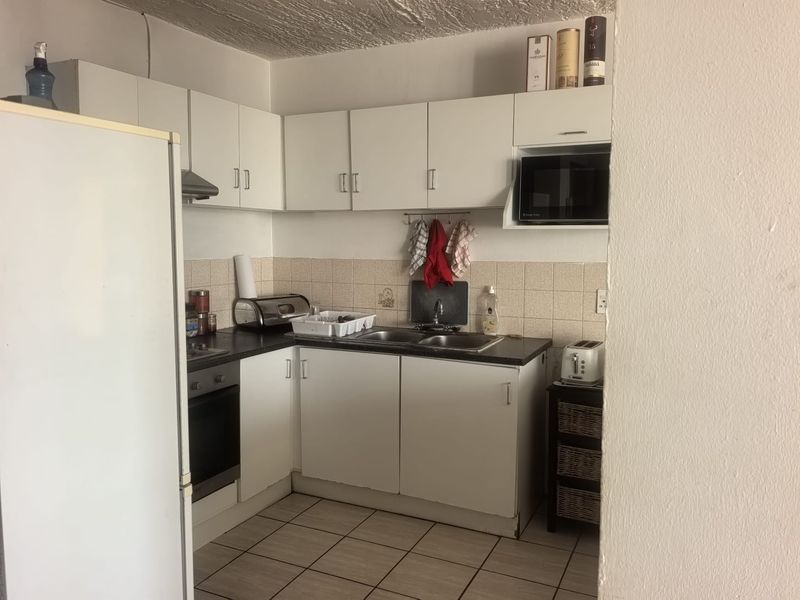 A functional kitchen featuring white cabinetry, a built-in oven, extractor fan, and tiled flooring, offering a practical layout for daily meal preparation.