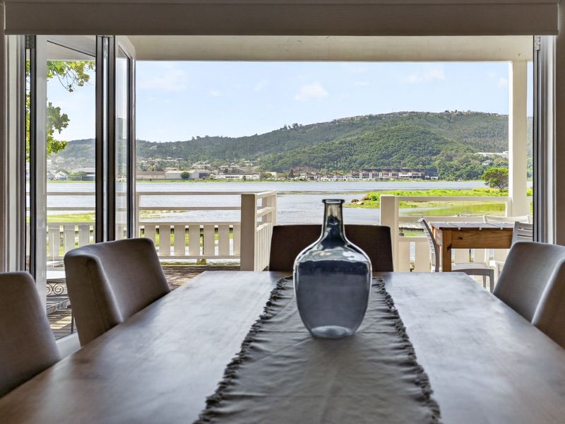 Dining area featuring large bi-fold doors that open onto a deck with scenic water and mountain views.