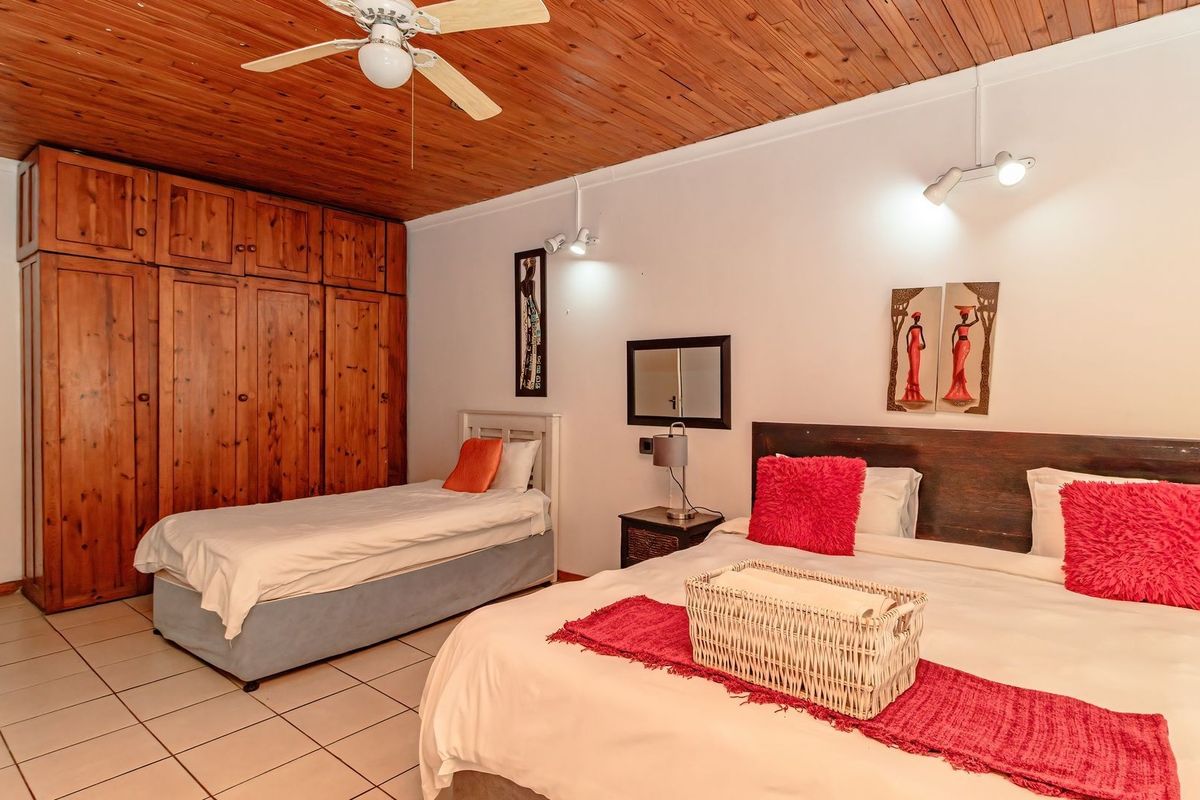 Spacious bedroom featuring a warm wooden ceiling, ceiling fan, tiled flooring, and extensive built-in wooden cabinetry for storage.