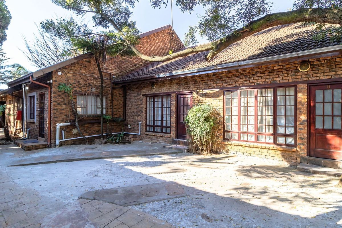 Rear exterior view of a commercial property featuring face brick construction, paved courtyard area, and multiple access points with timber-framed doors and windows.
