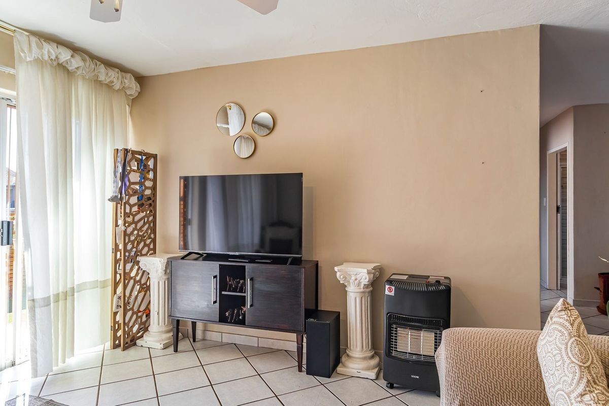 A living room featuring tiled flooring and a sliding glass door providing access to an outdoor patio area.