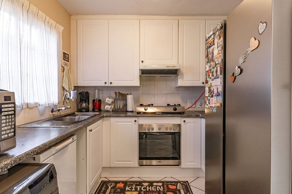 A functional kitchen featuring white cabinetry, granite-look laminate countertops, a built-in oven, gas hob, and an integrated extractor fan.