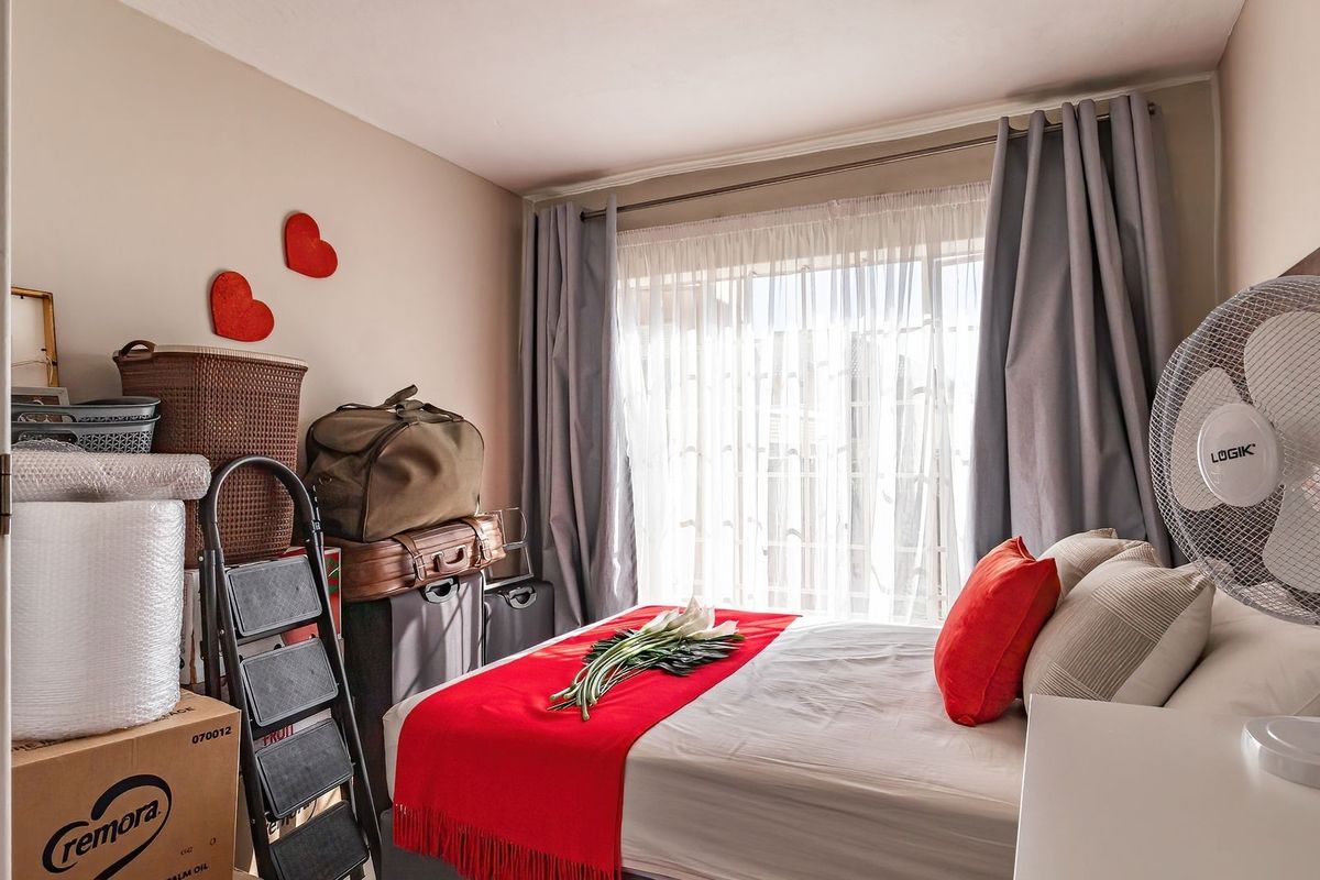 A bedroom featuring a large window with curtains, providing natural light to the space.