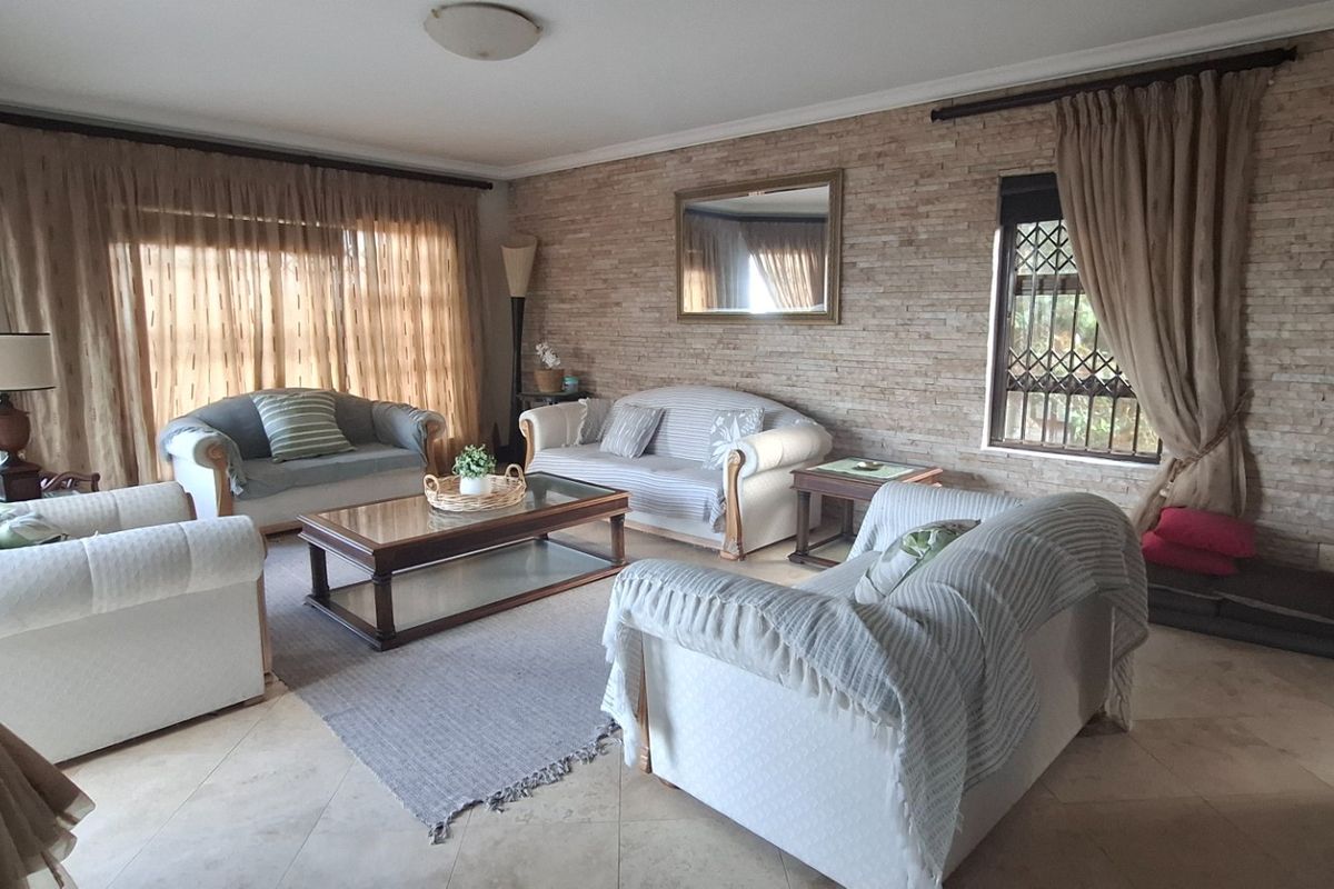 Spacious living room featuring a textured stone feature wall, large windows with natural light, and neutral tiled flooring.