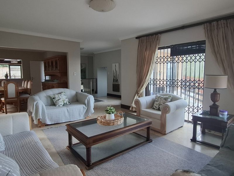 Spacious open-plan living and dining area featuring tiled flooring, large windows with security gates, and neutral wall finishes.