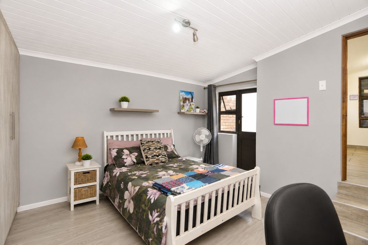A well-maintained bedroom featuring light wood-look flooring, a white tongue-and-groove ceiling, built-in cabinetry, and direct access to an outdoor area.