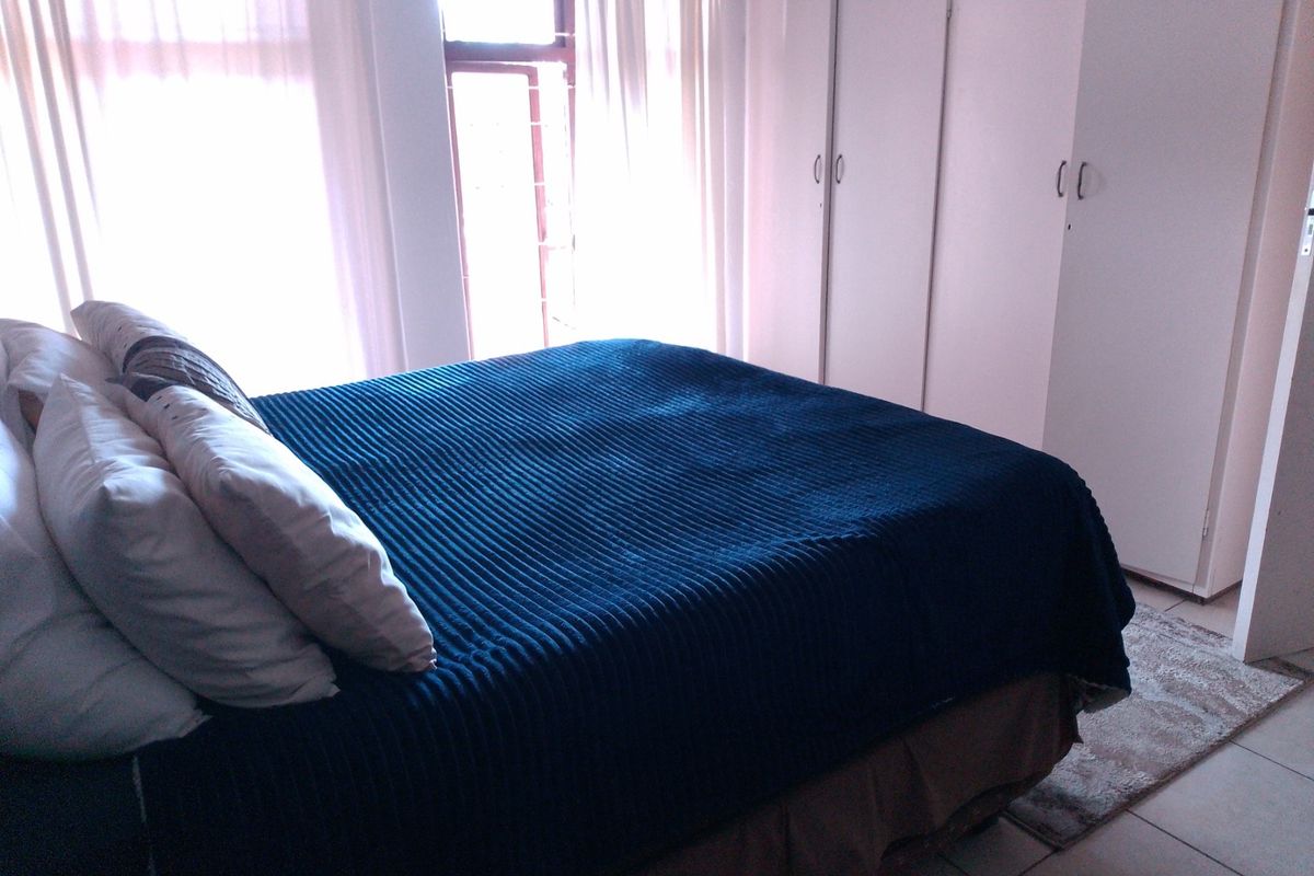A bright bedroom featuring built-in wardrobes and large windows allowing for ample natural light.