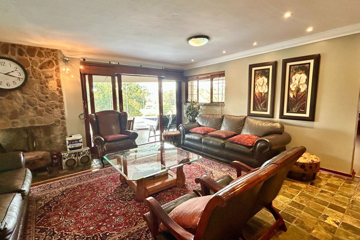 Spacious living room featuring a prominent stone fireplace, stone tile flooring, and large sliding glass doors providing access to the outdoor area.