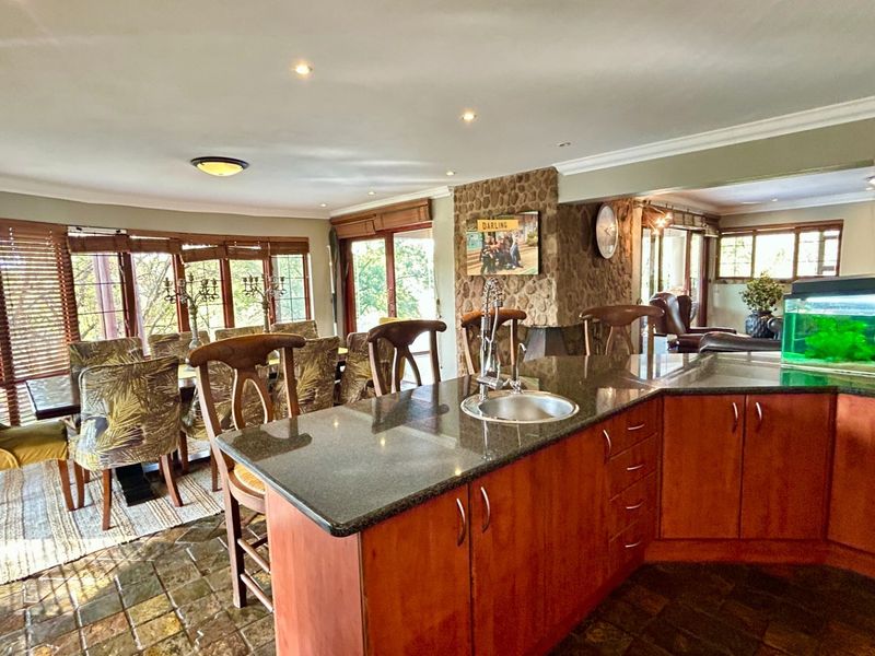 Open-plan kitchen and dining area featuring a stone feature wall, granite countertops, and slate tile flooring with abundant natural light.