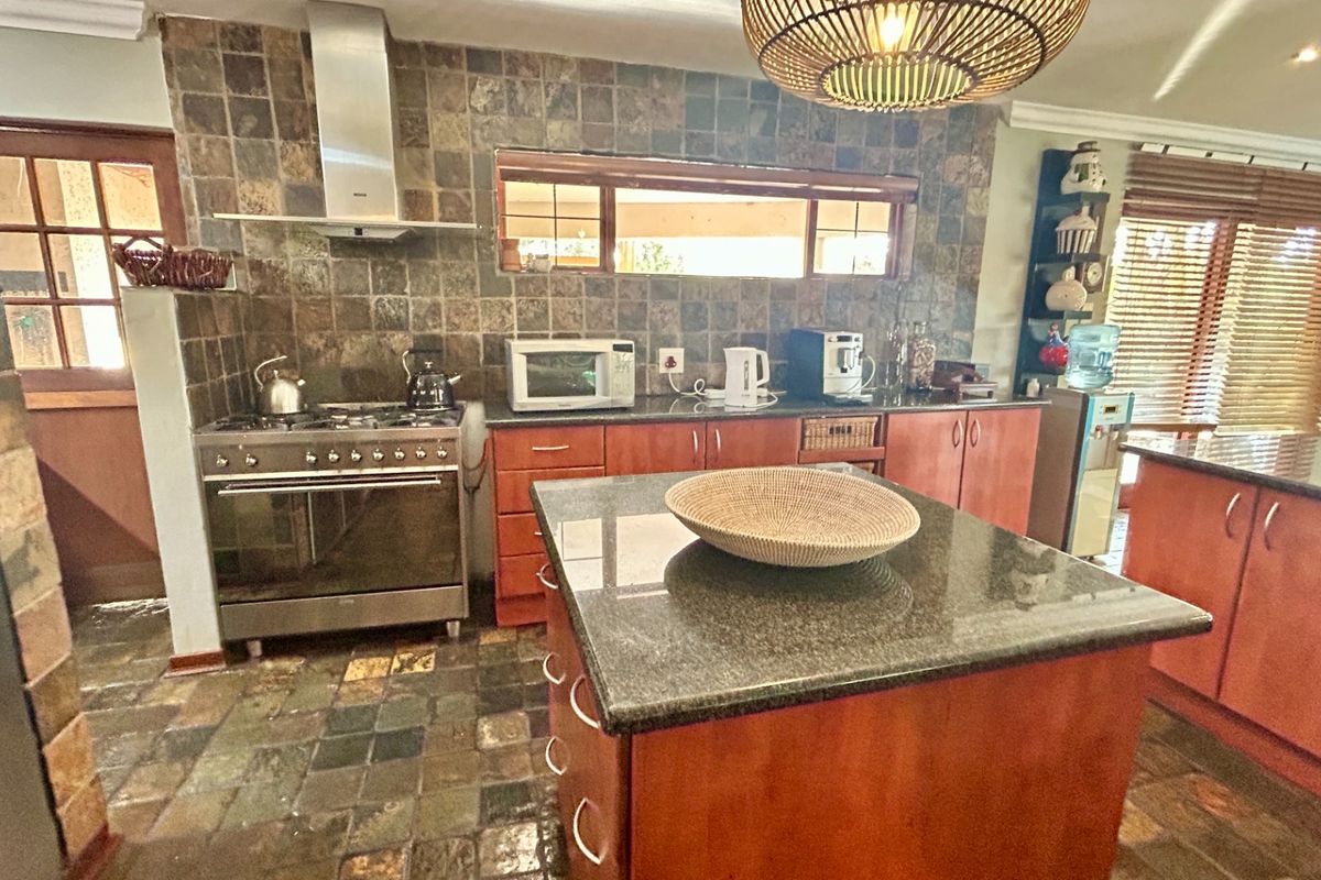 A functional kitchen featuring wooden cabinetry, granite countertops, a central island, and a stone tile backsplash with a stainless steel gas stove.
