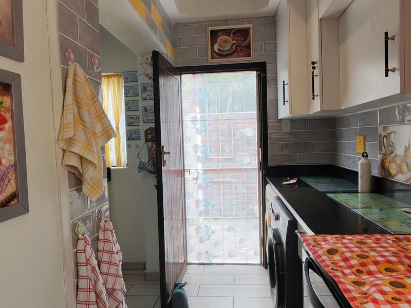A functional laundry area featuring built-in cabinetry, stone countertops, subway tile backsplash, and direct access to the exterior.