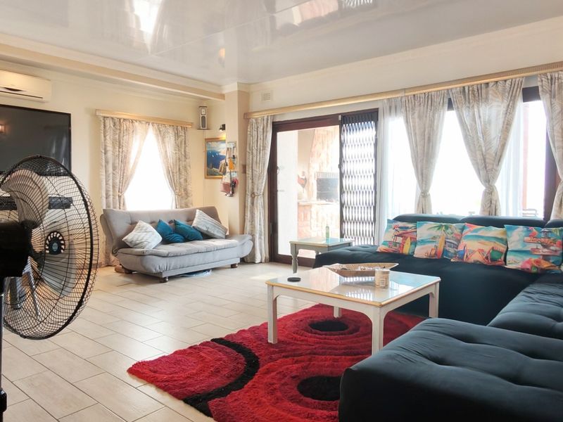 Spacious living room featuring tiled flooring, a split-system air conditioner, and large sliding glass doors providing access to the outdoor area.