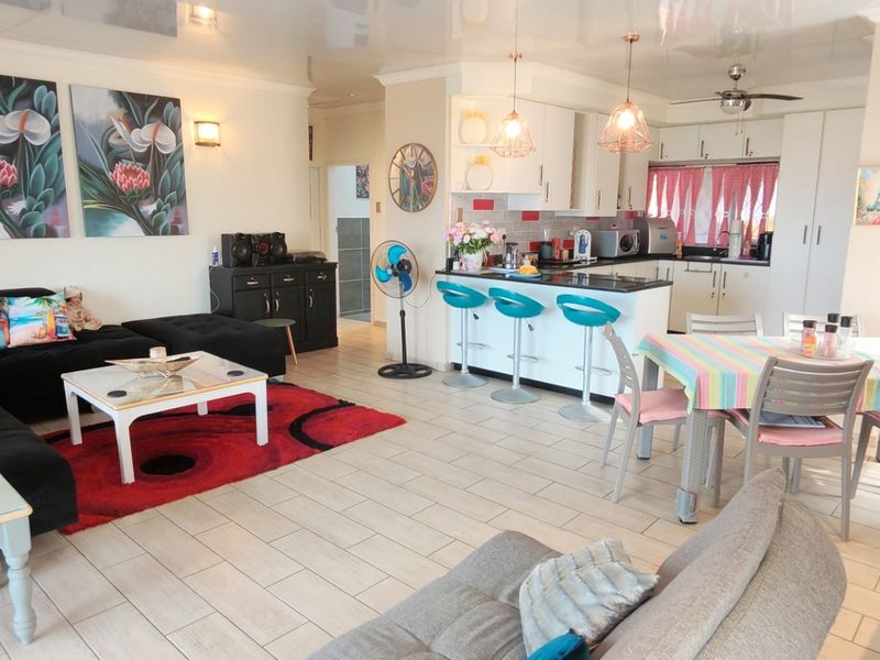 Spacious open-plan living area featuring a modern kitchen with island seating, tiled flooring, and integrated lighting, creating a functional and cohesive living space.