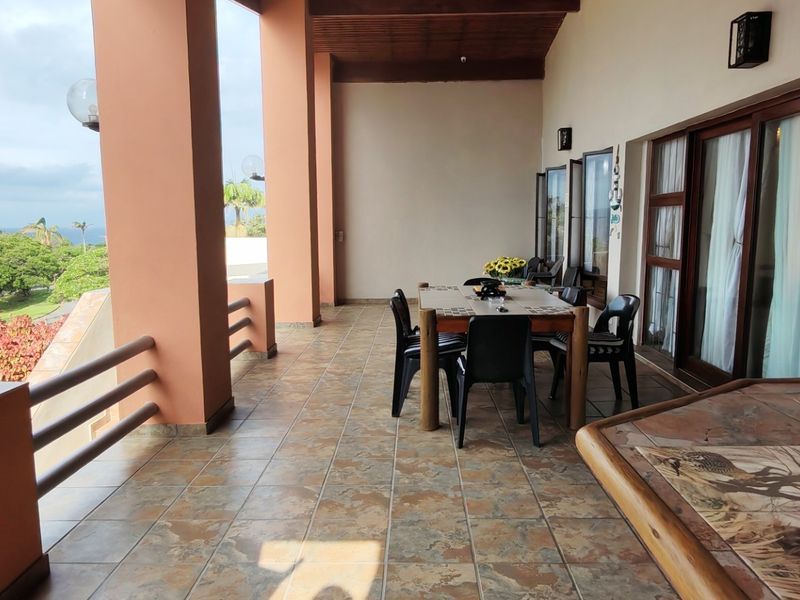 Spacious covered patio featuring tiled flooring, timber ceiling, and sliding glass doors, offering an ideal outdoor entertainment area with scenic views.