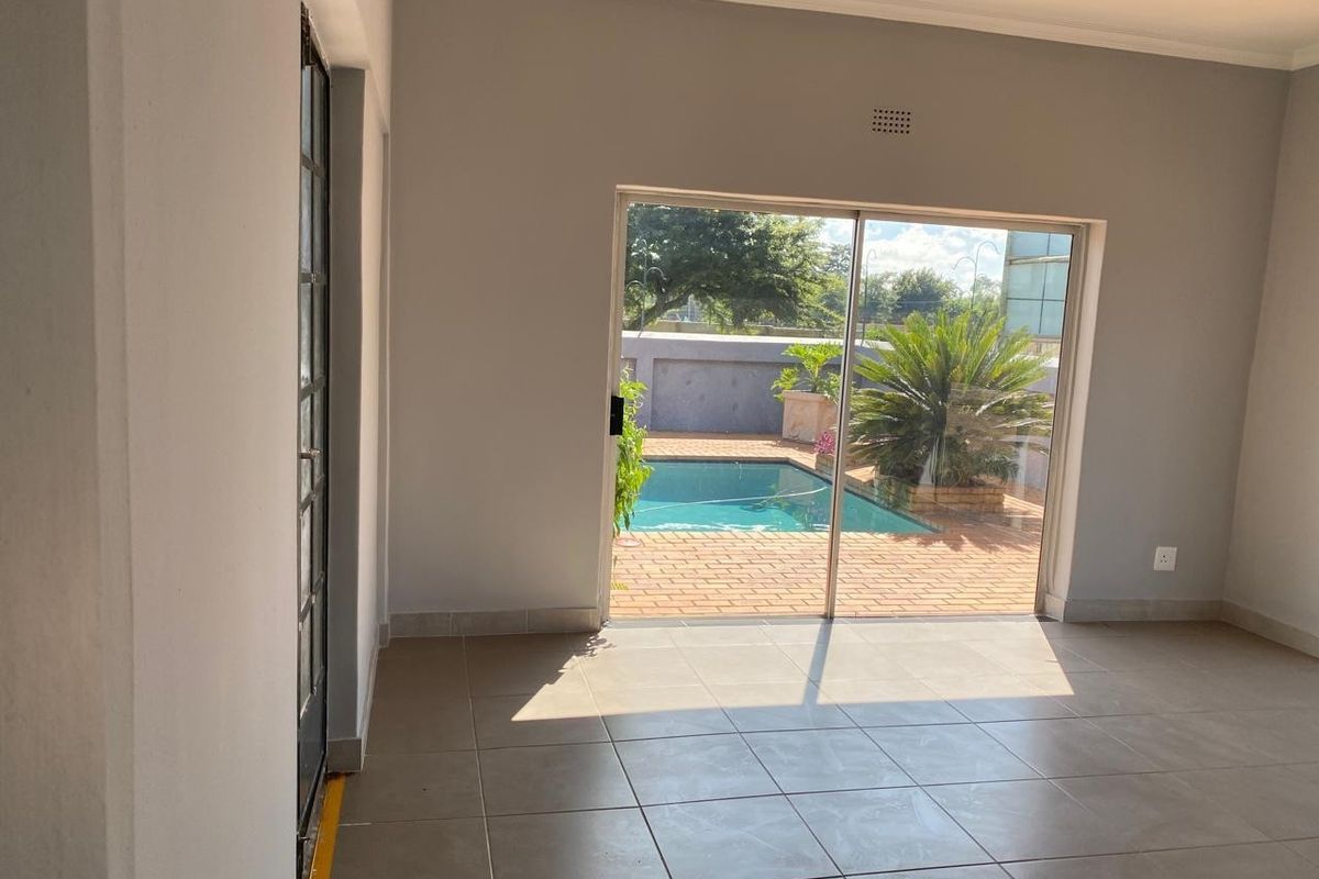 Bright living area featuring large sliding glass doors that open directly onto a paved patio and swimming pool area.
