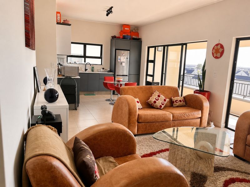 Open-plan living area featuring a modern kitchen with dark cabinetry and direct access to a private balcony through sliding glass doors.
