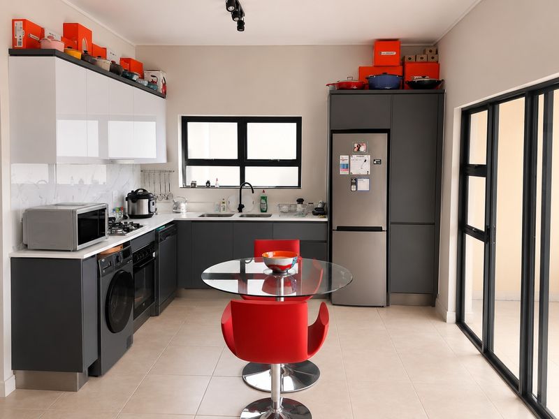 Modern open-plan kitchen featuring sleek grey cabinetry, marble-look splashback, integrated appliances, and direct access to an outdoor area through sliding glass doors.