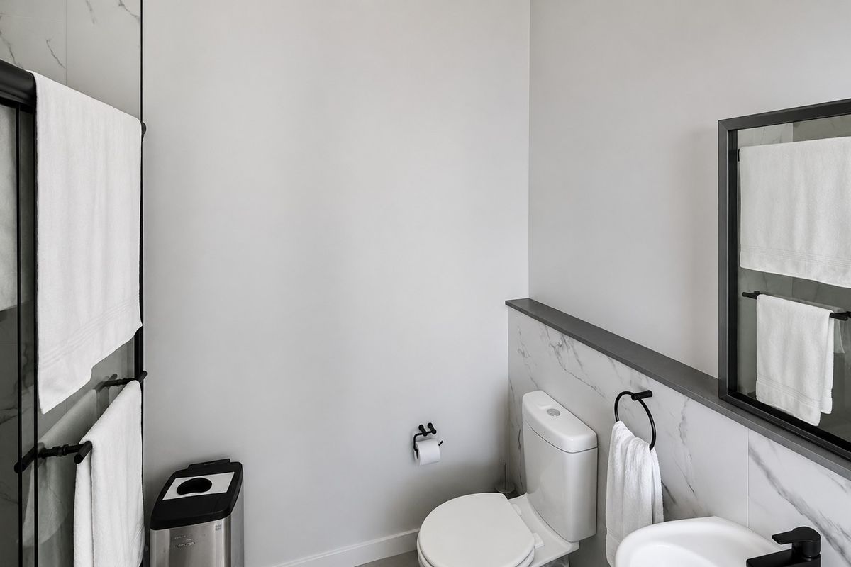 Modern bathroom featuring marble-look wall tiles, a sleek toilet, and contemporary black fixtures, creating a clean and sophisticated aesthetic.