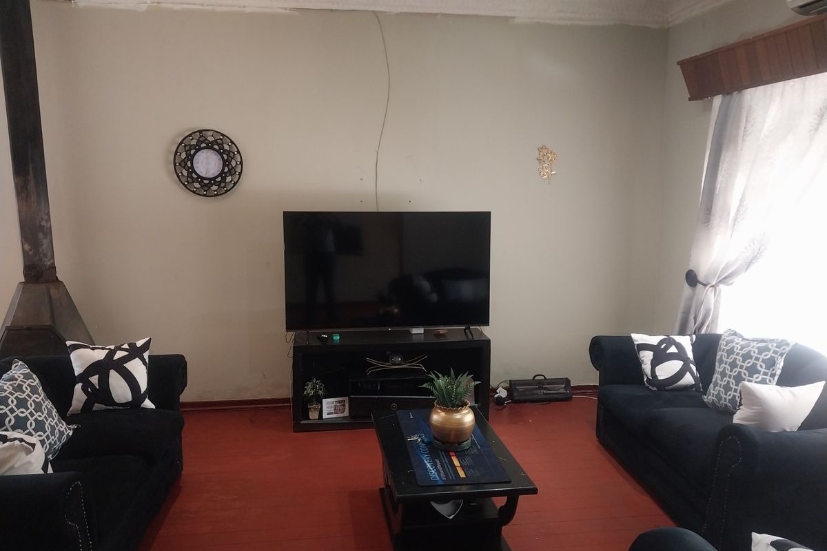 A living room featuring a built-in fireplace, painted walls with visible cracks, and traditional flooring.