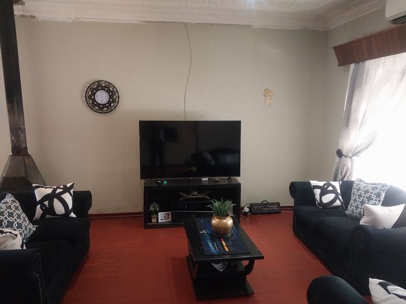 A living room featuring a built-in fireplace, painted walls with visible cracks, and traditional flooring.