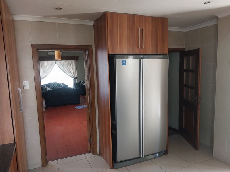A kitchen area featuring built-in wooden cabinetry and tiled flooring, with a doorway leading into an adjacent living space.