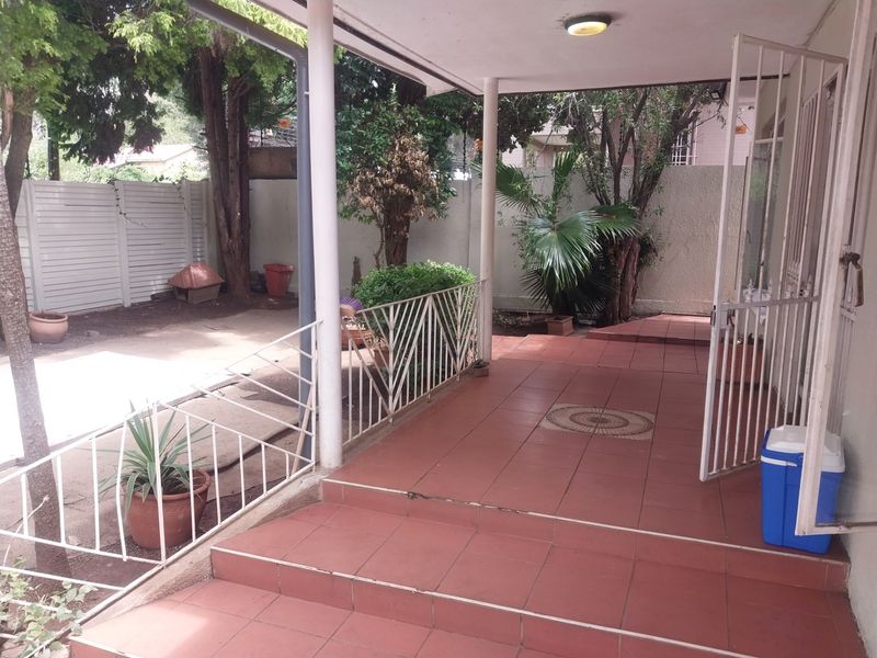 A covered patio area featuring tiled flooring, metal safety railings, and direct access to the rear garden space.