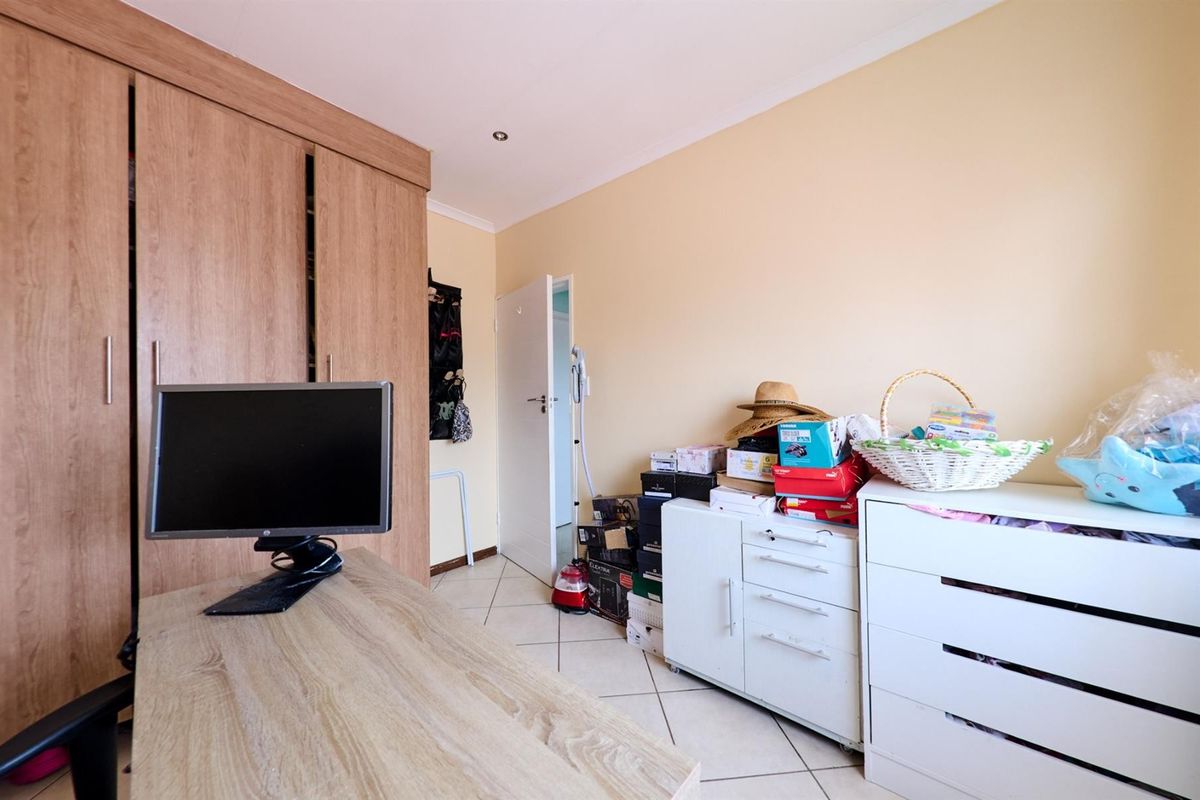 A bedroom featuring built-in wooden cupboards and tiled flooring, offering functional storage space and neutral wall finishes.