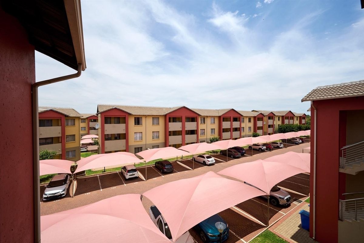 Elevated view of the apartment complex parking area featuring paved bays and shade cloth carports.