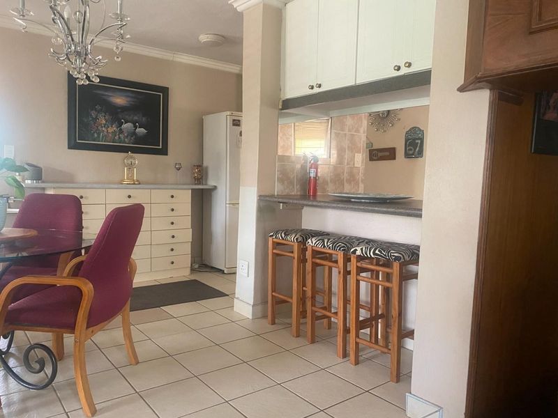 Open plan dining and kitchen area featuring tiled flooring, built-in cabinetry, and a breakfast bar counter.