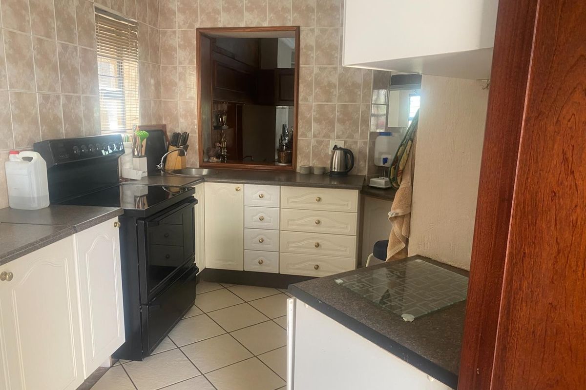 A functional kitchen featuring built-in cabinetry, laminate countertops, ceramic tile flooring, and a convenient pass-through window to the adjacent living area.