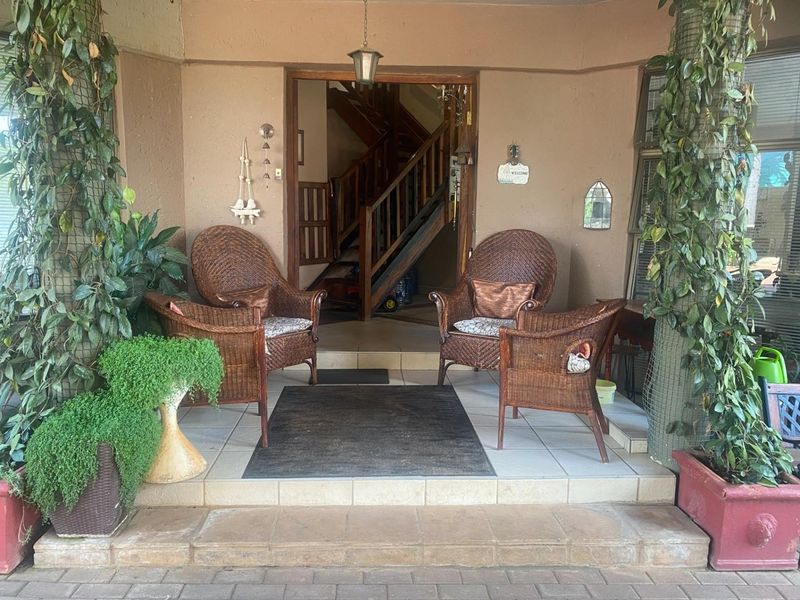 A covered patio entrance featuring tiled flooring and a view into the home's interior staircase area.