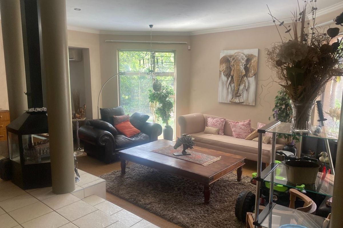 A spacious living room featuring a built-in fireplace, tiled flooring, and large windows that provide ample natural light.