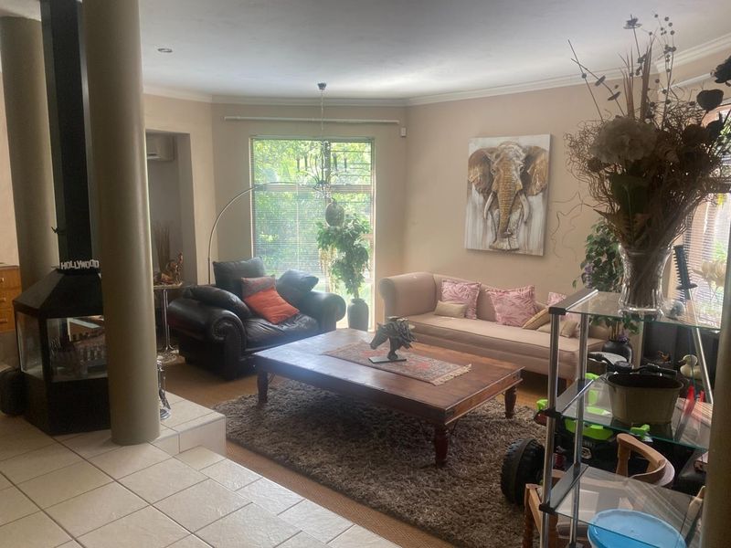 A spacious living room featuring a built-in fireplace, tiled flooring, and large windows that provide ample natural light.