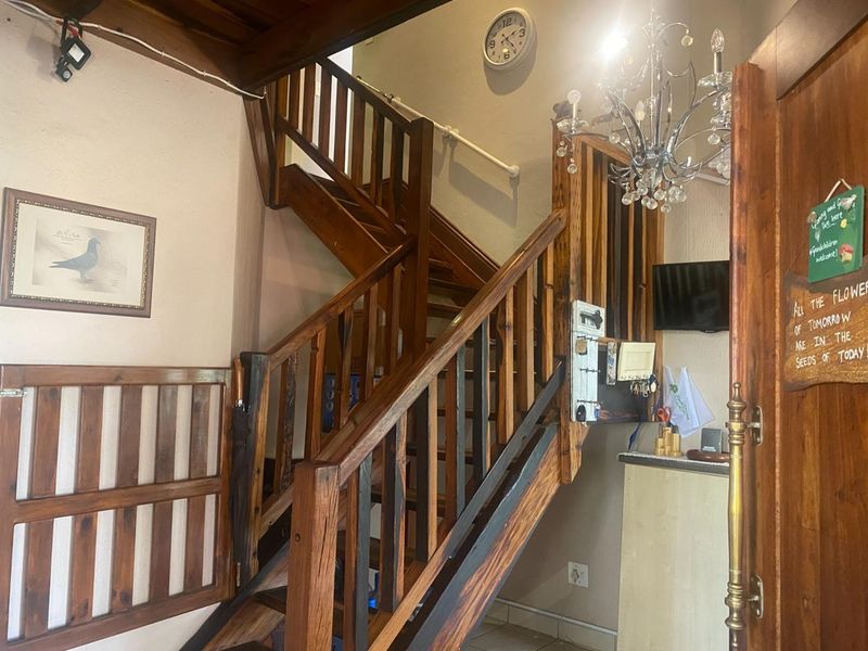 Entrance foyer featuring a prominent timber staircase with matching balustrade and exposed timber ceiling beams, providing a rustic aesthetic to the home's entry.