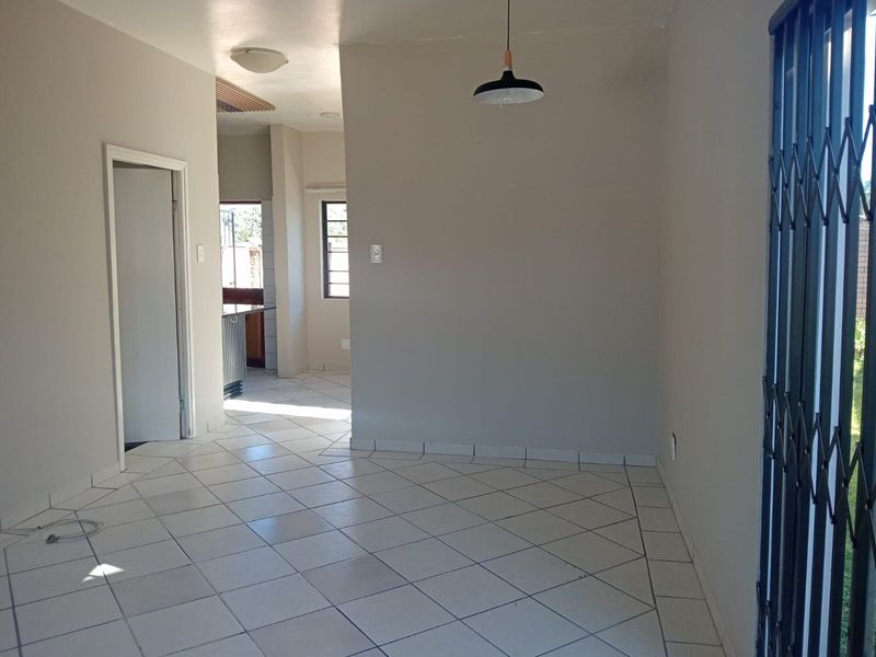 An open-plan living area featuring neutral walls, tiled flooring, and a security gate, providing a clean and versatile space for customization.