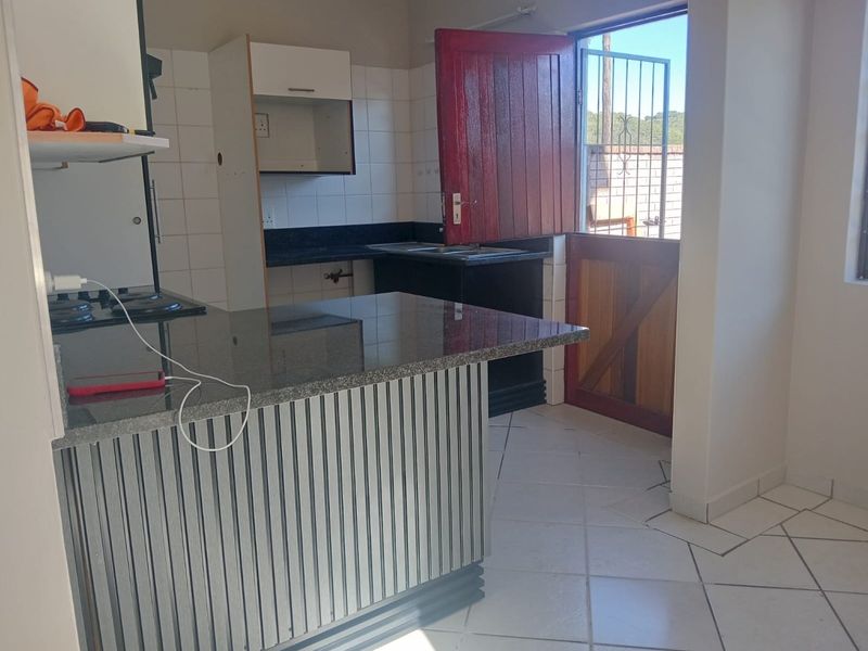 A functional kitchen area featuring granite countertops, a breakfast bar, and a stable door leading to the exterior, currently awaiting cosmetic updates.