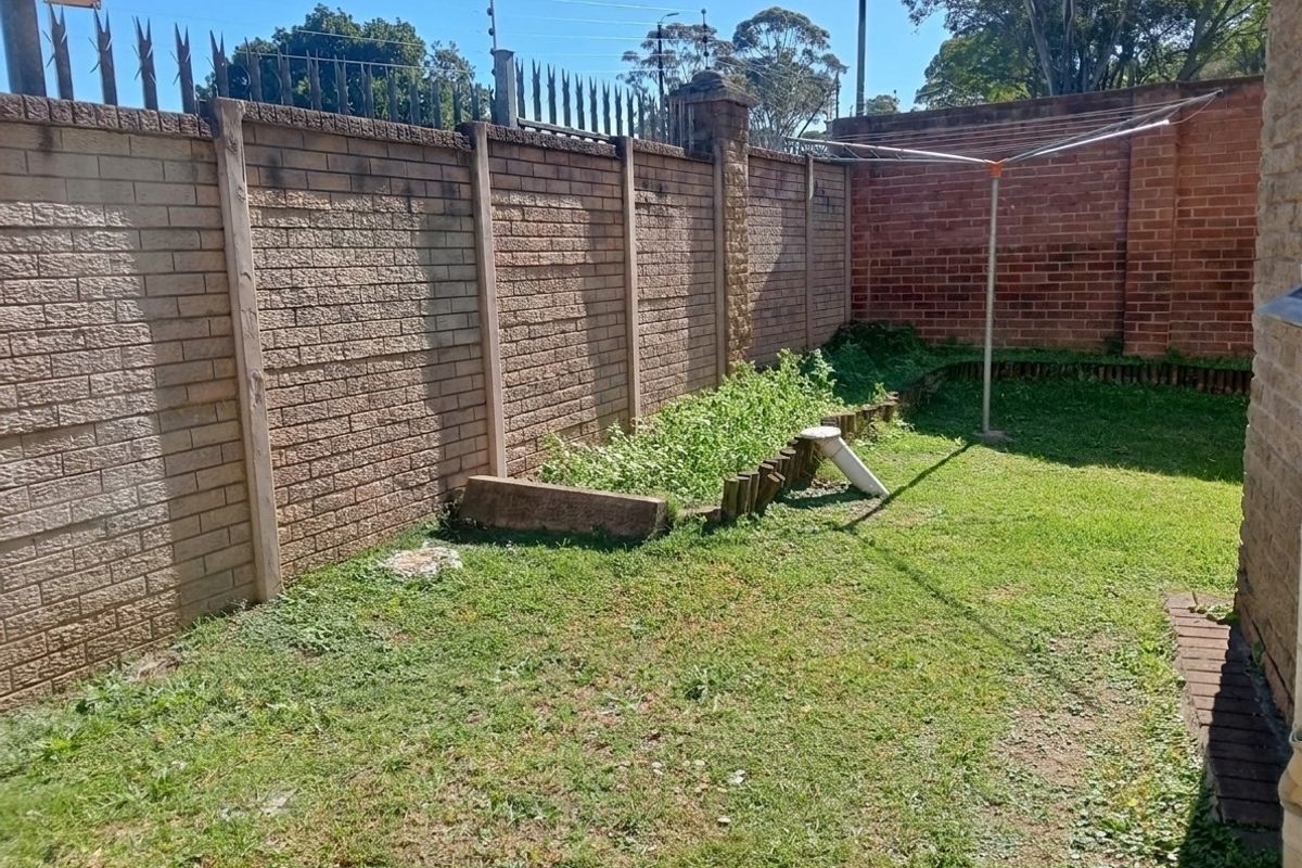 A private rear garden area featuring a brick boundary wall with electric fencing and a small raised garden bed.