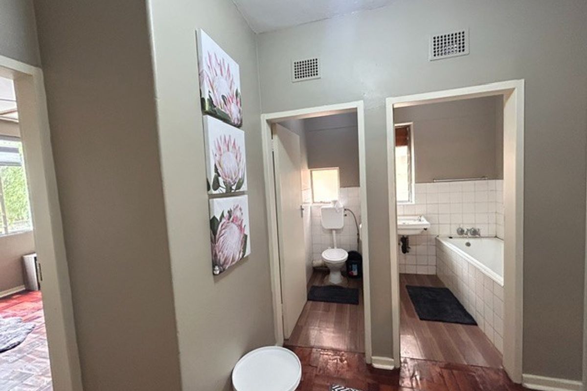 A functional bathroom layout featuring a separate toilet and a combined bath and basin area with tiled splashbacks.