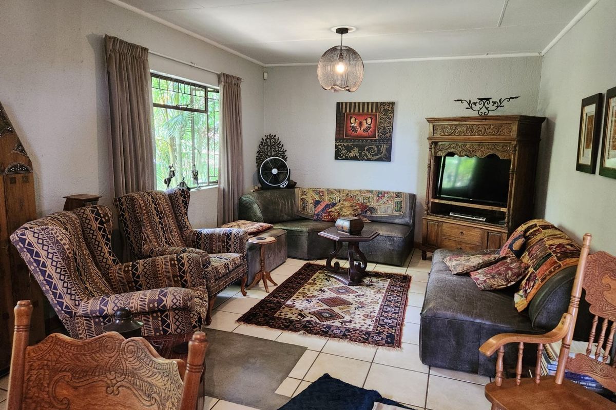 A comfortable living room featuring tiled flooring, large windows with security bars, and neutral wall finishes, offering a functional and lived-in space.