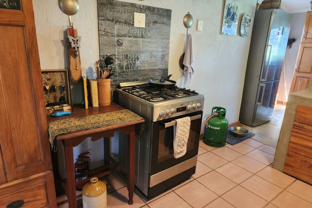 A functional kitchen area featuring a gas stove with a decorative splashback and tiled flooring, providing a practical cooking space.