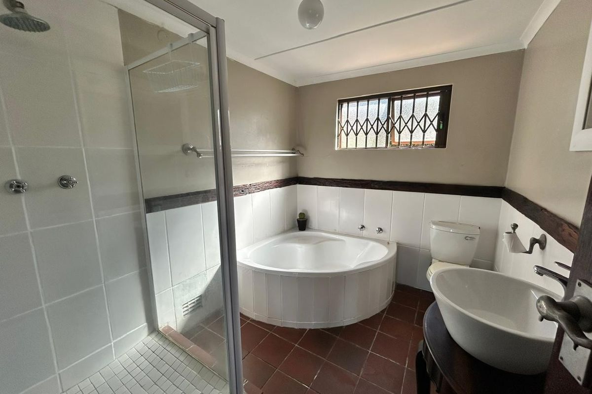 A functional bathroom featuring a corner bathtub, separate glass-enclosed shower, vessel sink, and tiled finishes, offering potential for modern updates.