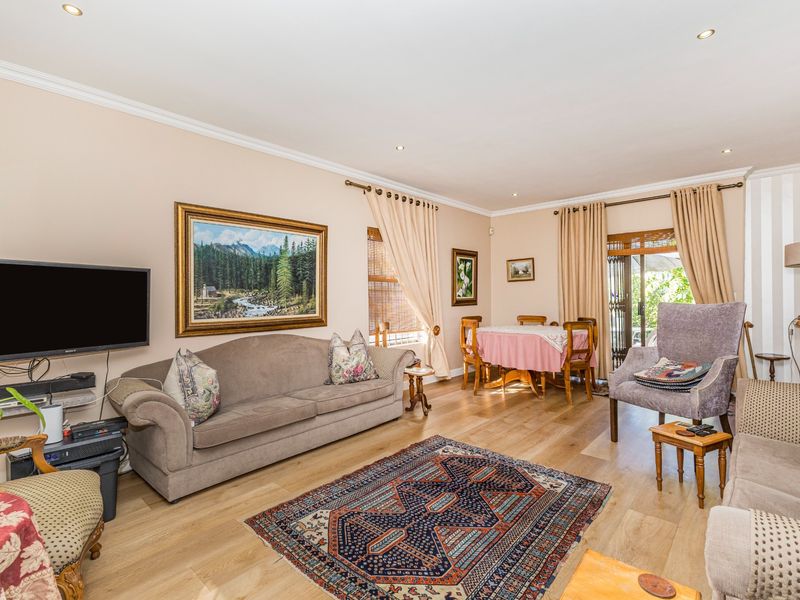 Spacious open-plan living and dining area featuring light timber flooring, recessed downlighting, and direct access to the outdoor space through sliding glass doors.