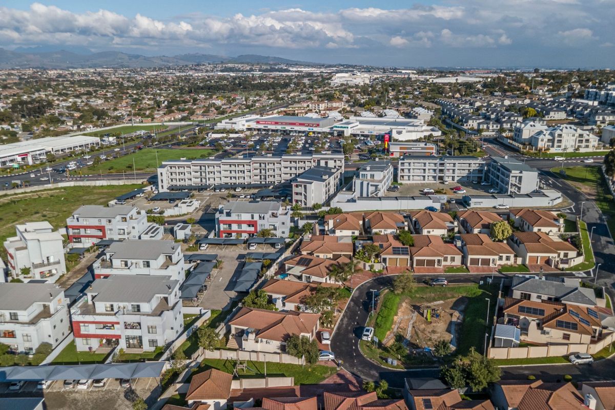 Aerial view of a residential estate featuring a mix of detached houses and apartment complexes with surrounding infrastructure and commercial areas.