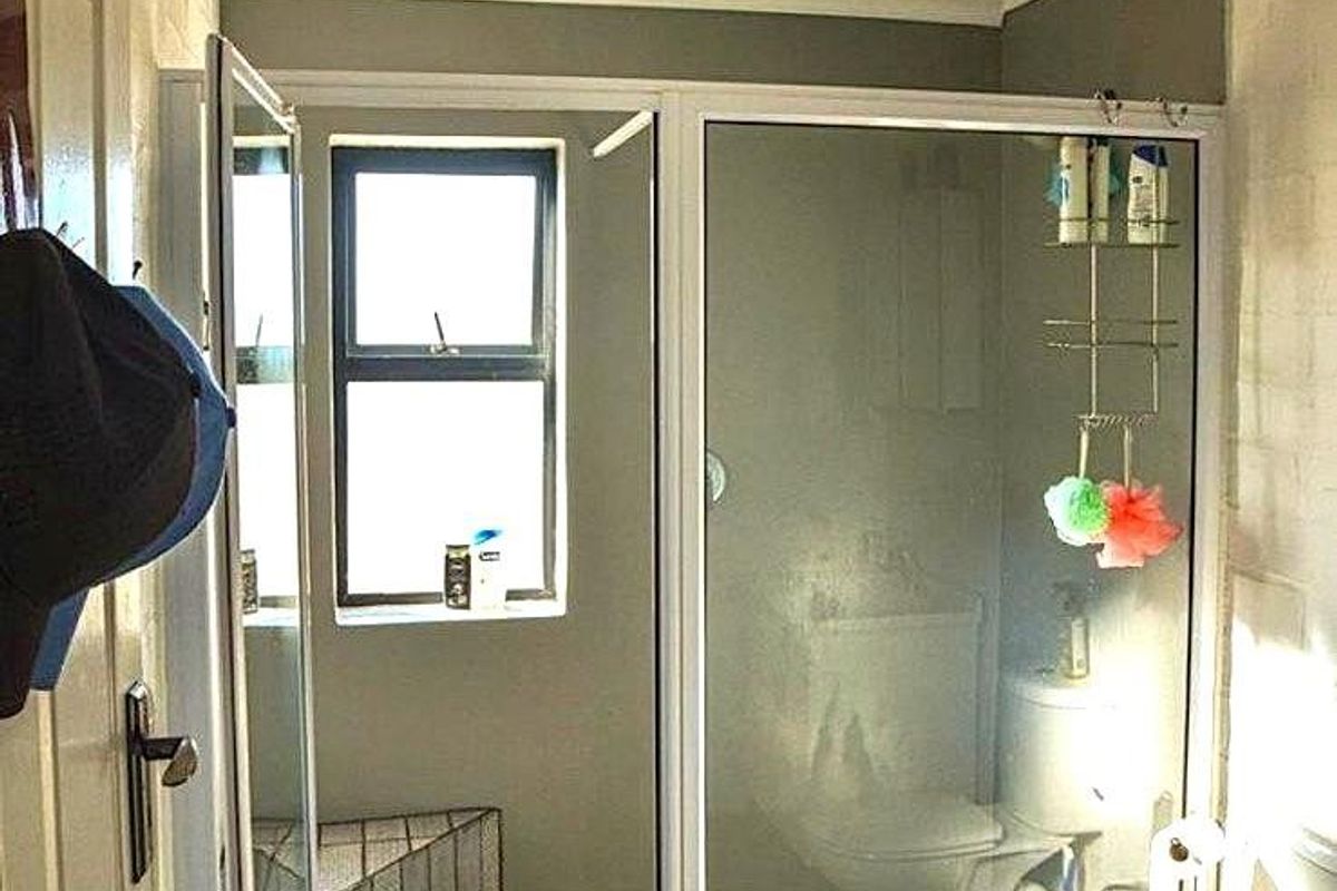 A functional bathroom featuring a walk-in shower with pebble-style flooring, a white toilet, and a tongue-and-groove ceiling finish.