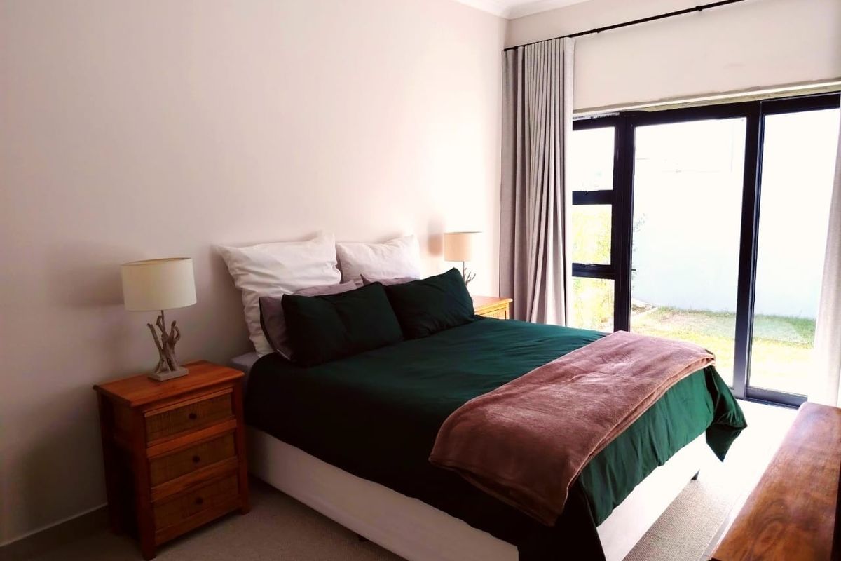 A well-lit bedroom featuring large sliding glass doors that provide direct access to the outdoor garden area.