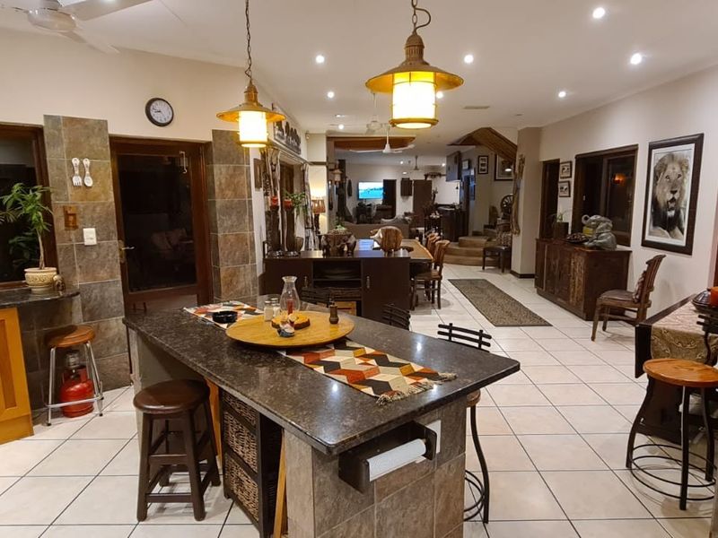 Spacious open-plan living area featuring a central granite kitchen island, tiled flooring, and stone-clad accents, creating a warm and functional family space.