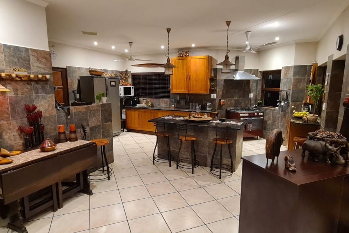 Spacious kitchen featuring a central island, stone tile backsplash, wooden cabinetry, and tiled flooring, offering a functional layout for cooking and casual dining.