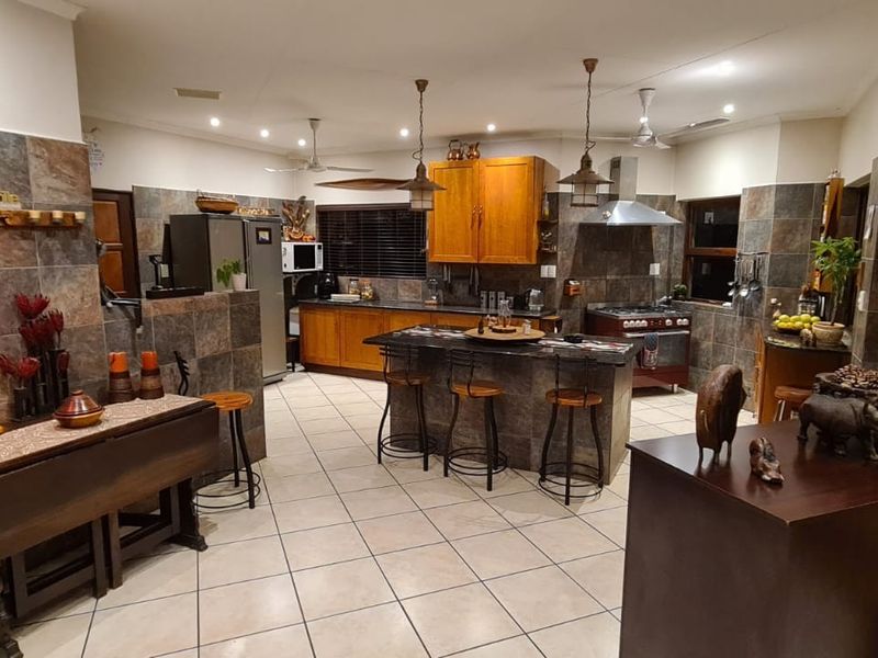 Spacious kitchen featuring a central island, stone tile backsplash, wooden cabinetry, and tiled flooring, offering a functional layout for cooking and casual dining.